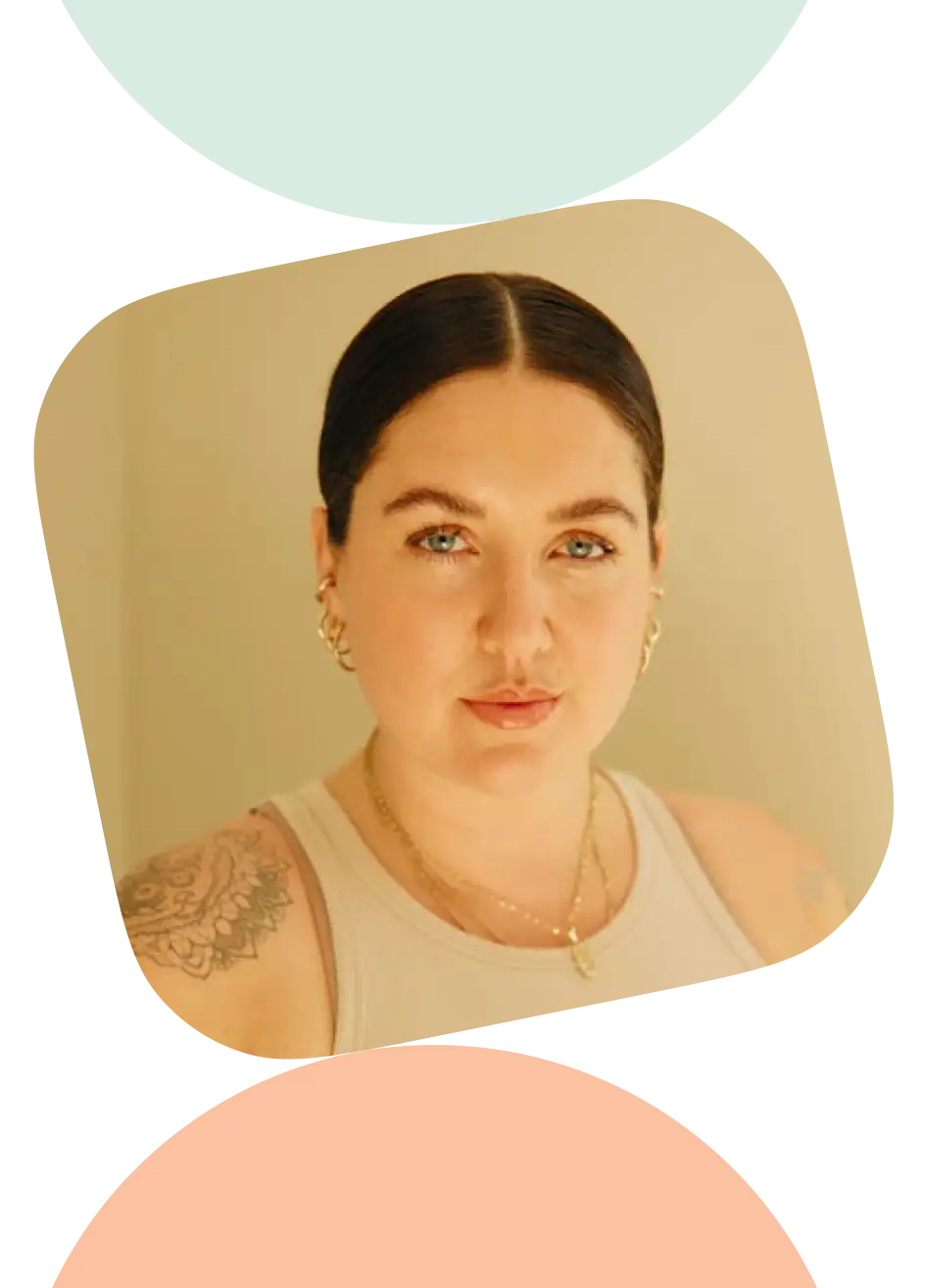 A woman with tattoos wearing a white tank top.